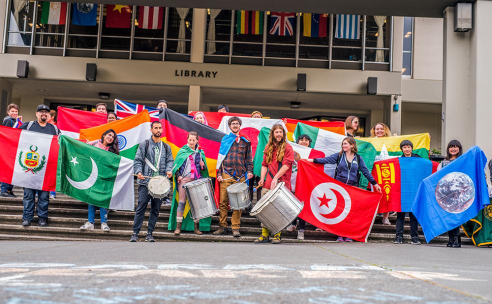 Cal Poly Humboldt students gather in front of the Library to showcase flags from more than a dozen countries for Internal Education Week’s Welcome Ceremony and Flag Parade.