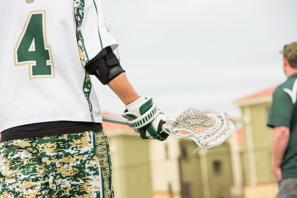 Humboldt men's lacrosse player holds a lacrosse stick, also known as a crosse
