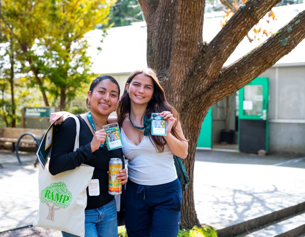 A photo of two students posing for a photo while holding up their Spring Preview name tags. 