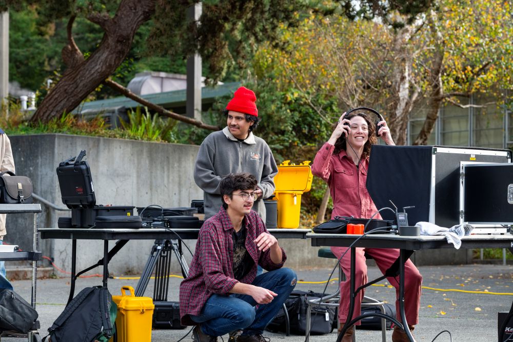 A photo of two students and Art + Film Professor Sarah Lasley working on a film project near the Van Duzer Theatre.