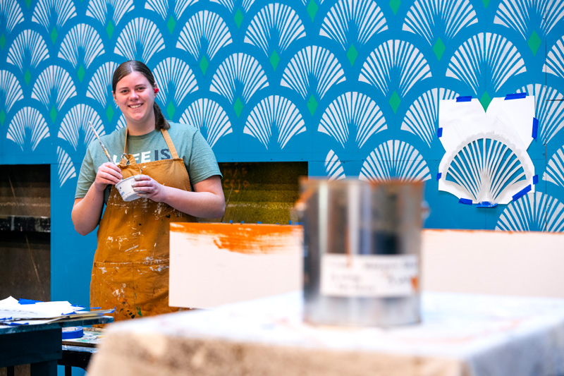 A person is painting a wall with a roller in a well-lit room