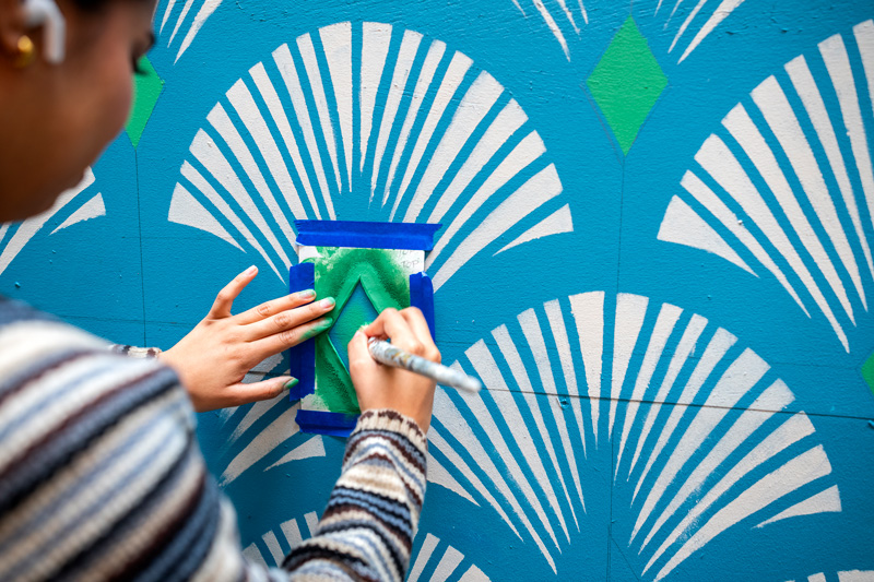 A person painting a blue and white wall with fans