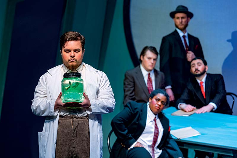 Actor holding large jar of liquid