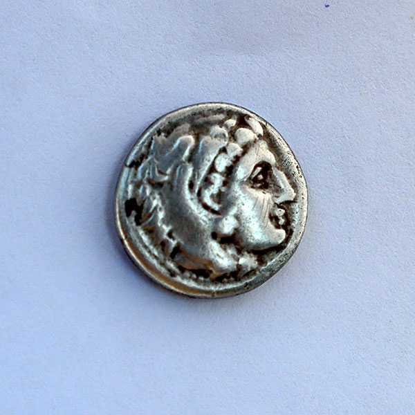 A silver coin featuring the head of a man, showcasing intricate details and a polished finish