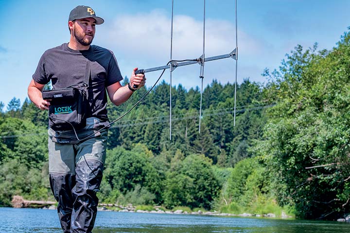 Natural Resources graduate student James Whelan uses a hand-held antenna to mobility track and locate signals from radio tags implanted
                            on fish.