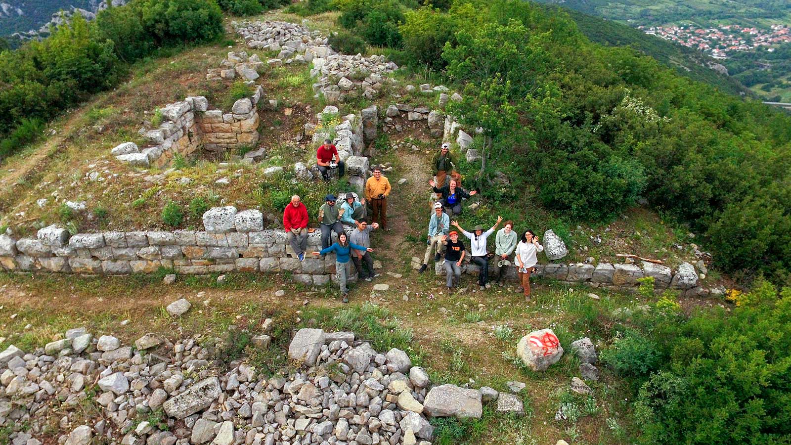 A group of people standing triumphantly on a mountain peak, enjoying the panoramic view around them