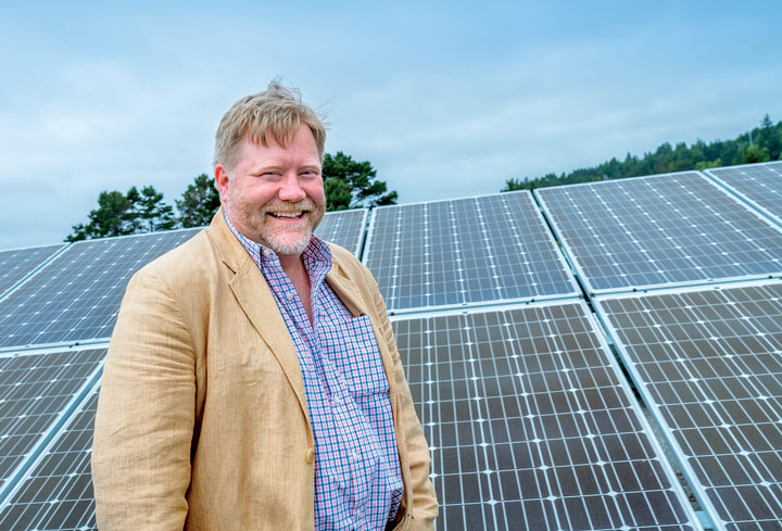 Arne Jacboson standing in front of solar panels