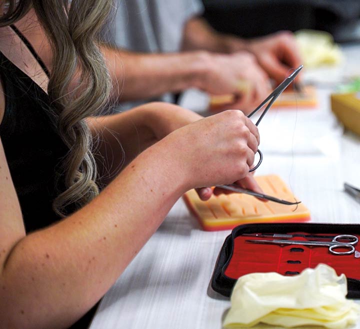 Student summer interns in the Healthcare Career Pathways Program, launched by Biology Professor and pre-med advisor Jianmin Zhong, learn how to suture in the Library. 