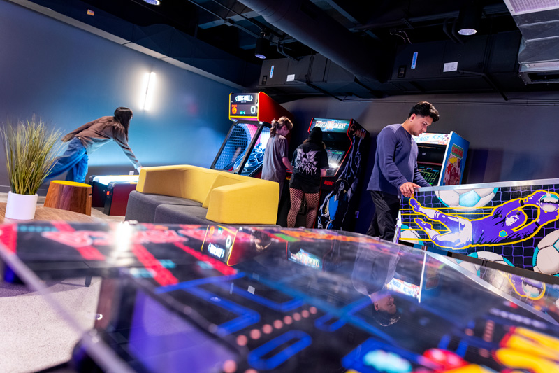 A group of diverse people enjoying video games together in a lively arcade setting