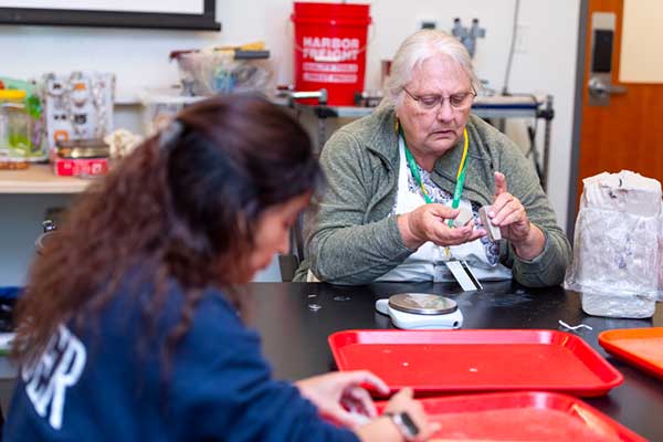 With the guidance of Instructor Barbara Klessig (right), students in the Experimental Anthropology Lab use clay to reconstruct artifacts that they believe to be loom weights. Photo by Kellie Jo Brown.