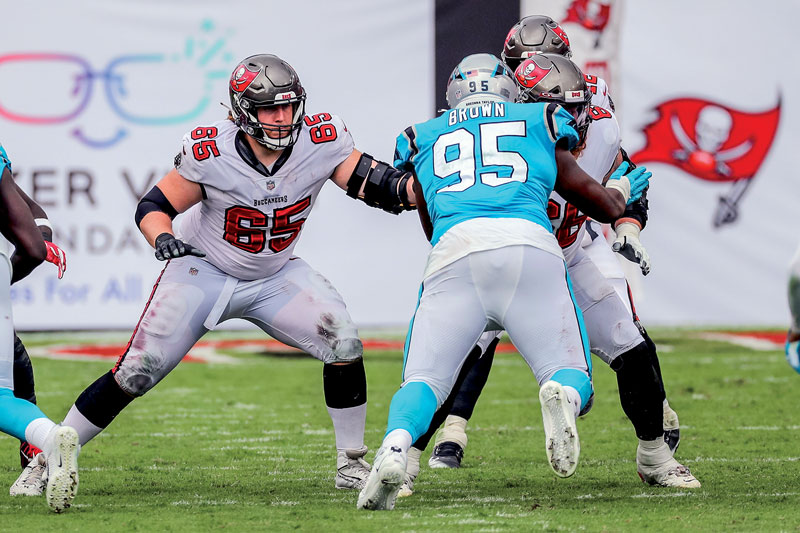 a group of football players at a game pushing up against one another