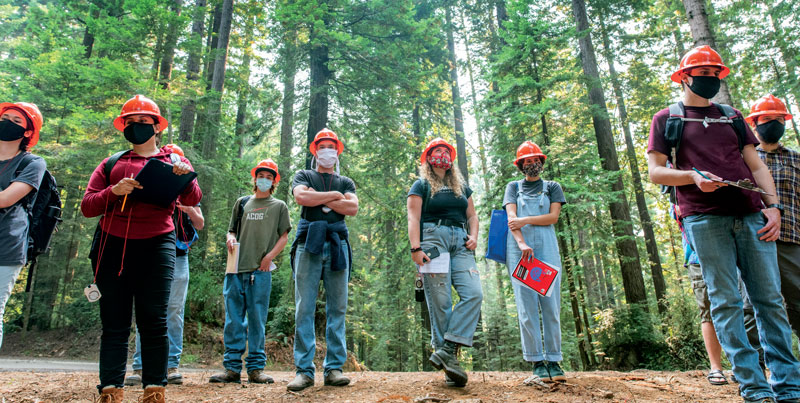 group of students standing in the forest with hard hats and masks on
