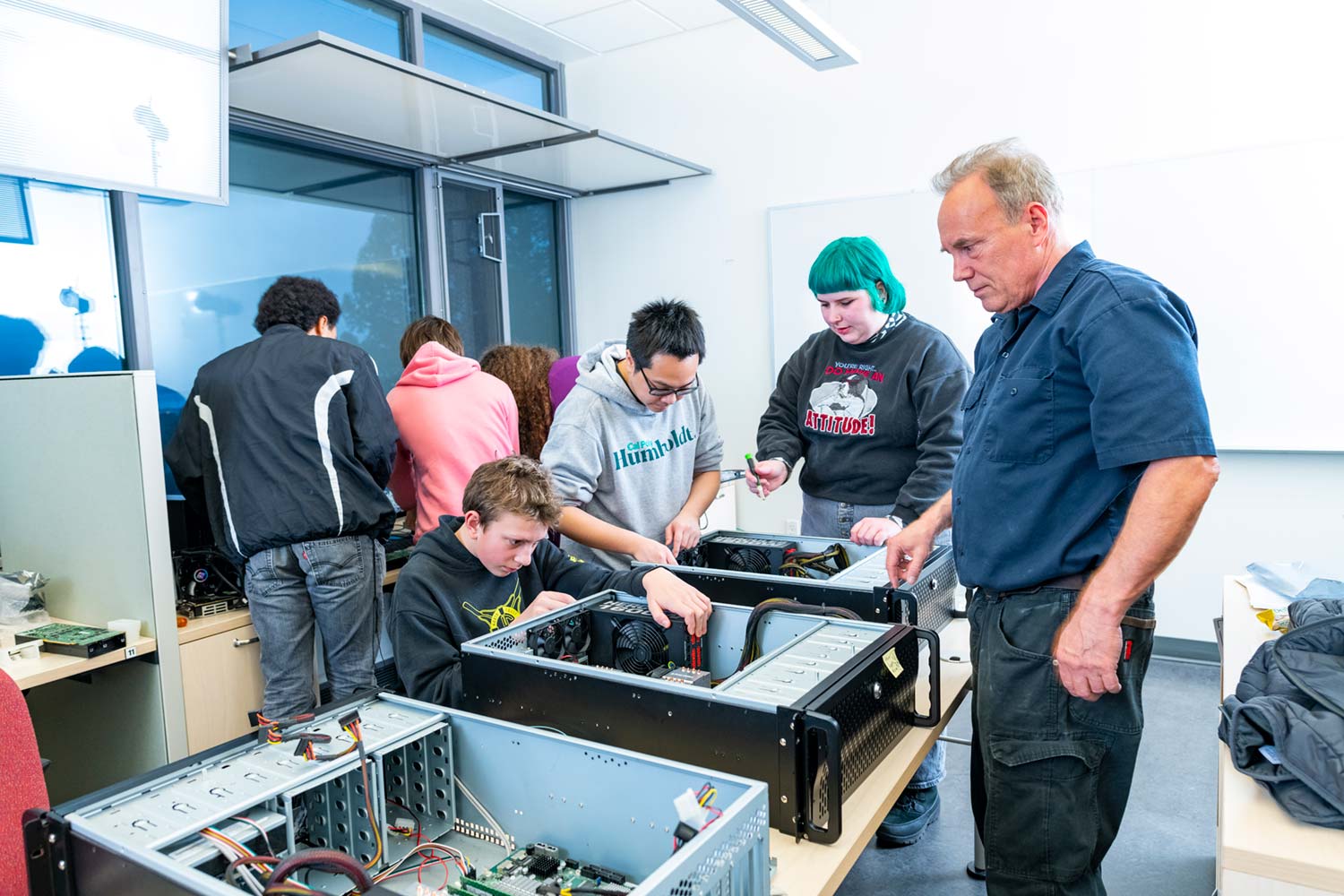 Students and faculty work with computer equipment in a campus lab.