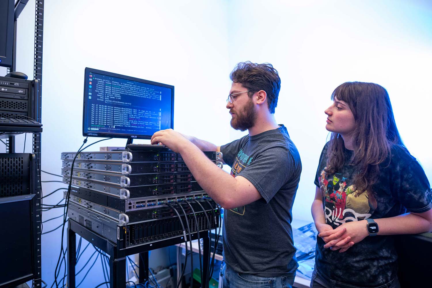 Students and faculty work with computer equipment in a campus lab.
