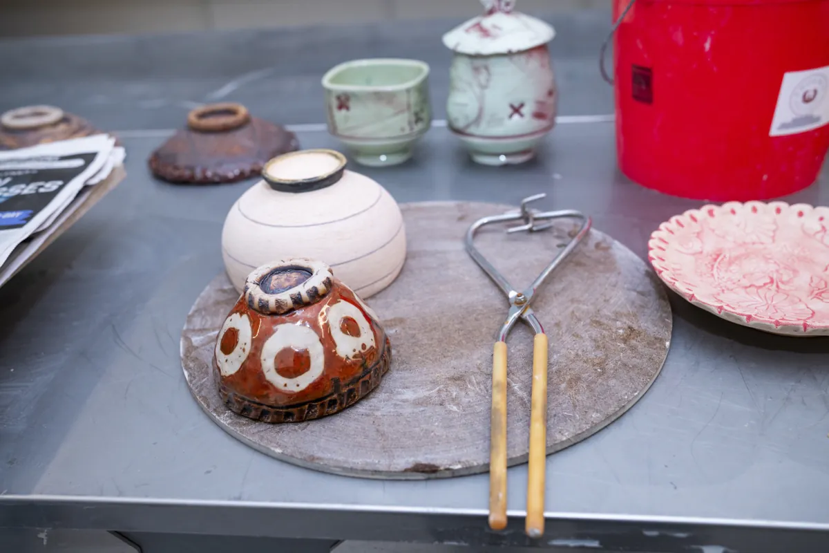 Glazed ceramic pieces and trimming tools on a studio work surface