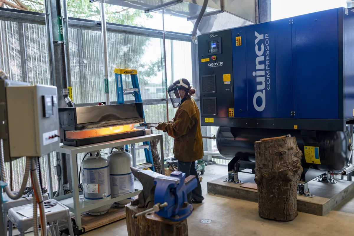 Student in protective gear working at heated metalworking equipment in Jenkins Hall
