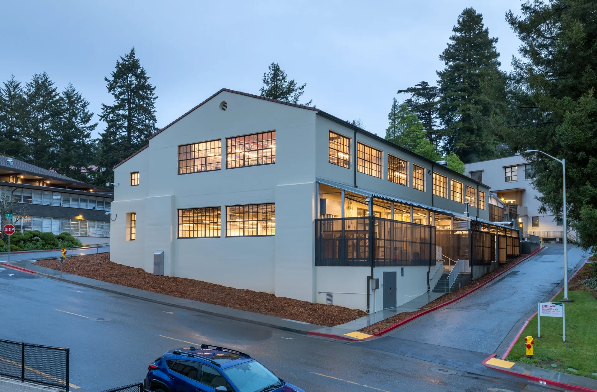 Evening exterior of the renovated Jenkins Hall with light glowing through the studio windows