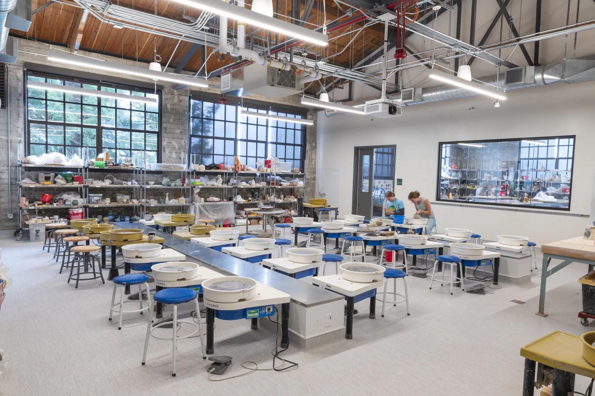 Wide view of the renovated Ceramics Studio with pottery wheels and students working