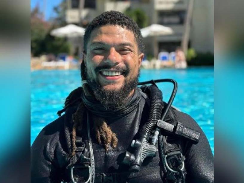 Person in wetsuit holding a fish