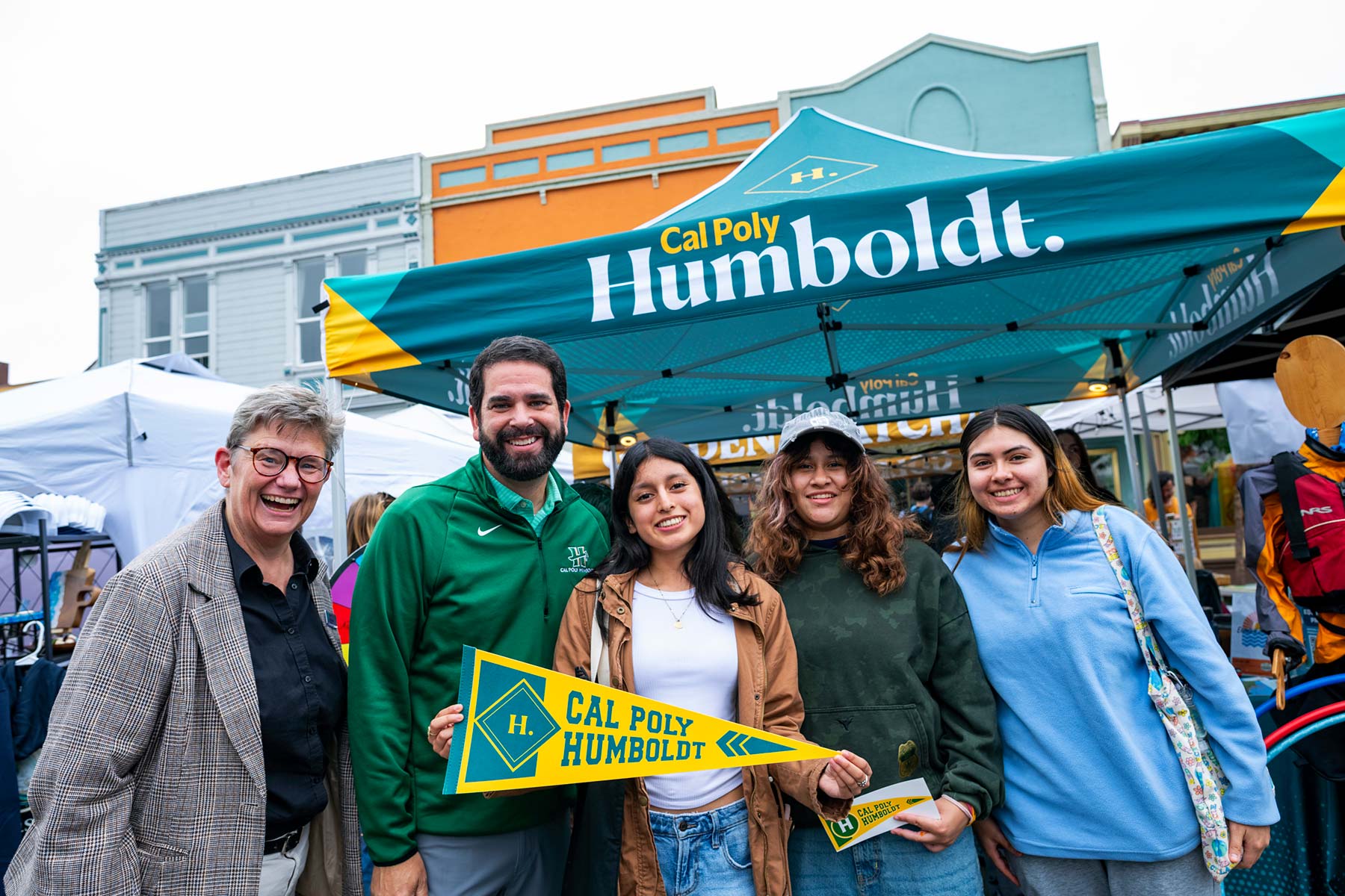 Richard Carvajal poses with four students beneath a Cal Poly Humboldt canopy.