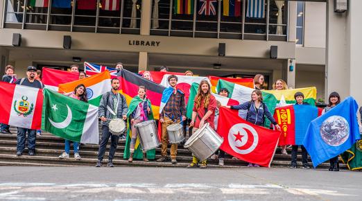 Cal Poly Humboldt students gather in front of the Library to showcase flags from more than a dozen countries for Internal Education Week’s Welcome Ceremony and Flag Parade.