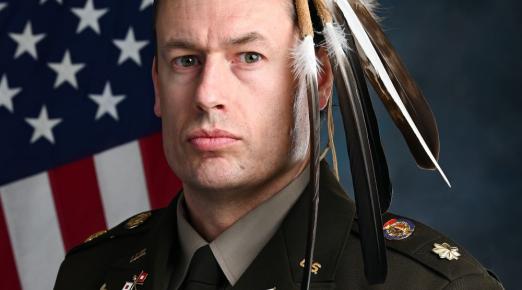 A portrait of Maj. Patrick Sorensen wearing his Native American regalia of feathers while wearing his U.S. Army uniform. 