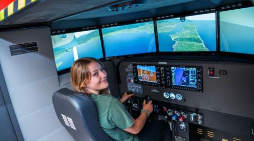 A photo of Humboldt student Harmony Switzer Tryon using the flight simulator at the Library. 