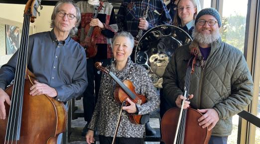 The concert's musicians standing on a staircase with their instruments in hand and smiking. 