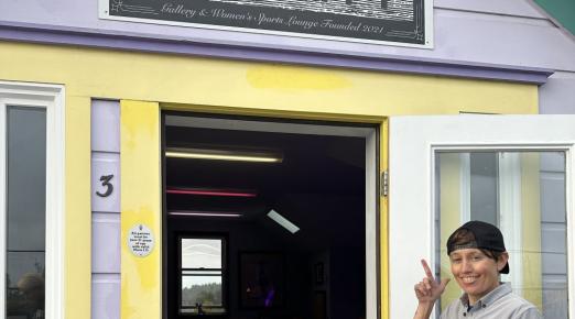 A photo of Michelle Cartier pointing at The Summitt sign at the entrance of The Summitt