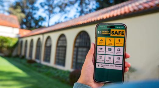 A photo of someone holding a smart phone with the new Cal Poly Humboldt SAFE App's home screen. 