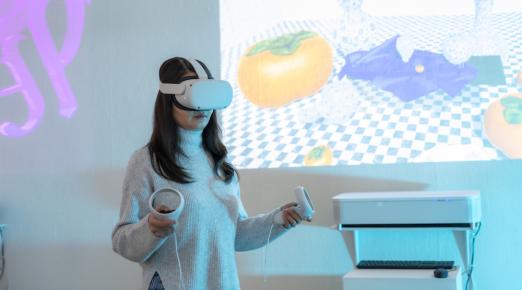 a female standing with a VR set on their head and an image of a table setting projected on the wall behind them. 