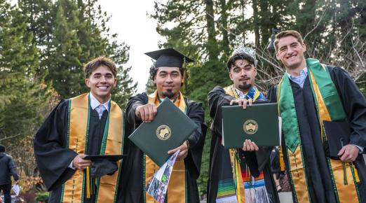 A photo of graduates showing off their diploma covers at Fall Commencement 2024.