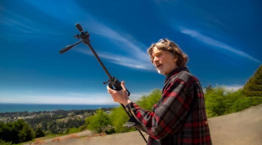 A photo of Ray Olson holding a tripod while filming an episode of Humboldt Outdoors.