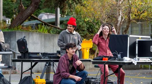 A photo of two students and Art + Film Professor Sarah Lasley working on a film project near the Van Duzer Theatre.