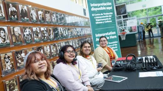 Four people sitting at a table with a banner behind them that describes the center for Translation & Interpretation services