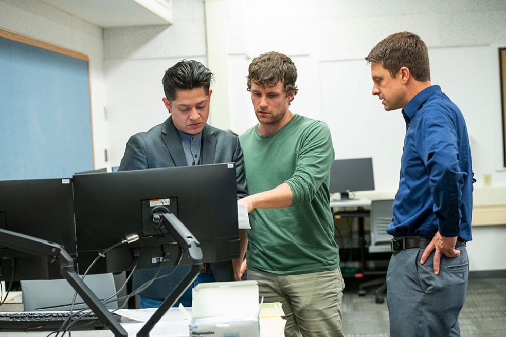 Associate Professor Josh Zender ( right) and students Francky Mirafuentes ( left), and Daniel Taylor (center) at the on-campus VITA tax clinic on Wednesday, Feb. 8.