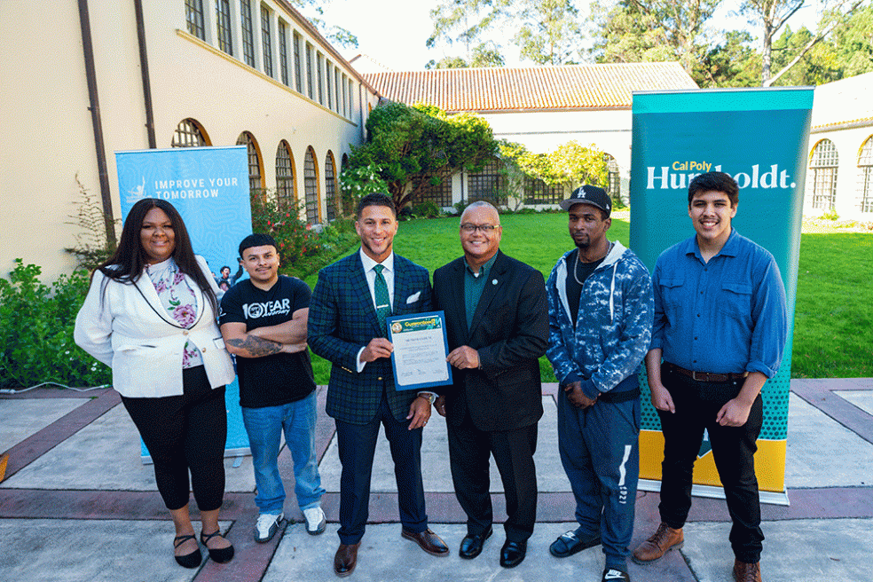 Improve Your Tomorrow CEO (center left) and Cal Poly Humboldt President Tom Jackson, Jr. (center right) stand with students at a signing ceremony. 