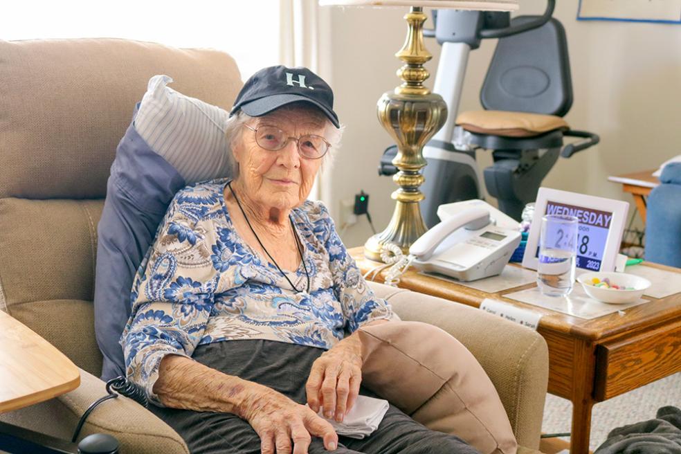 A photo of 102-year-old alum Sarah Franklin sitting on a chair wearing a Humboldt &quot;H dot&quot; baseball cap. 