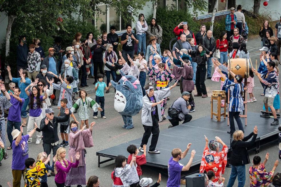 a crowd gathers around a small stage to watch dance performances 