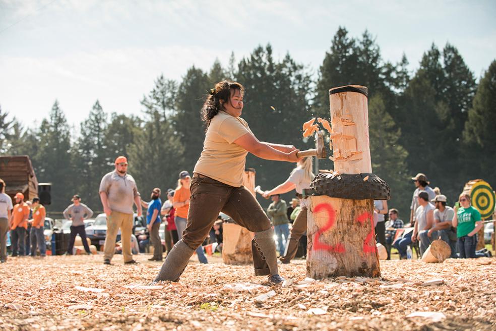 A photo of a Logging Sports team member chopping a log with an axe. 