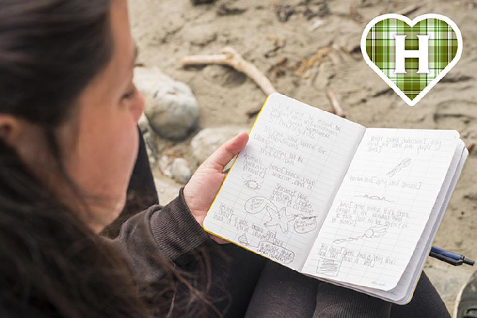 HSU student studies notebook on beach