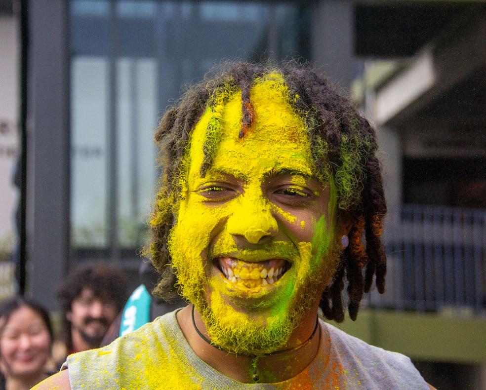 Alex Anderson's award-winning photo of Dakari Tate, a Cal Poly Humboldt Wildlife major whose face is covered in yellow powder for the Holi festival outside the Gutswurrak Student Activities Center on March 24, 2023.
