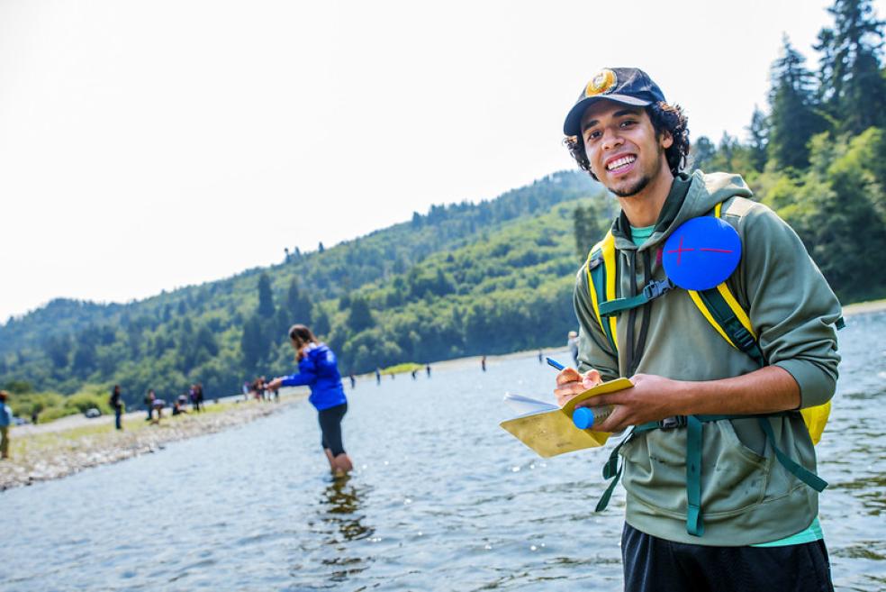 A photo of a student standing in the Klamath River taking notes. 