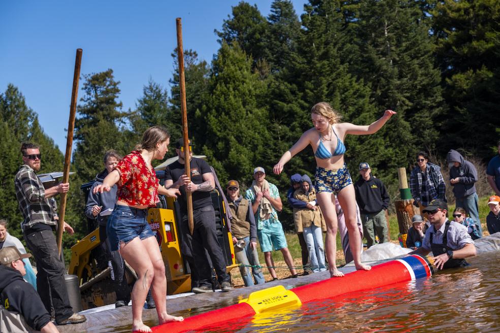 Two contestants battle it out while balancing on a floating makeshift log during the birling competition.