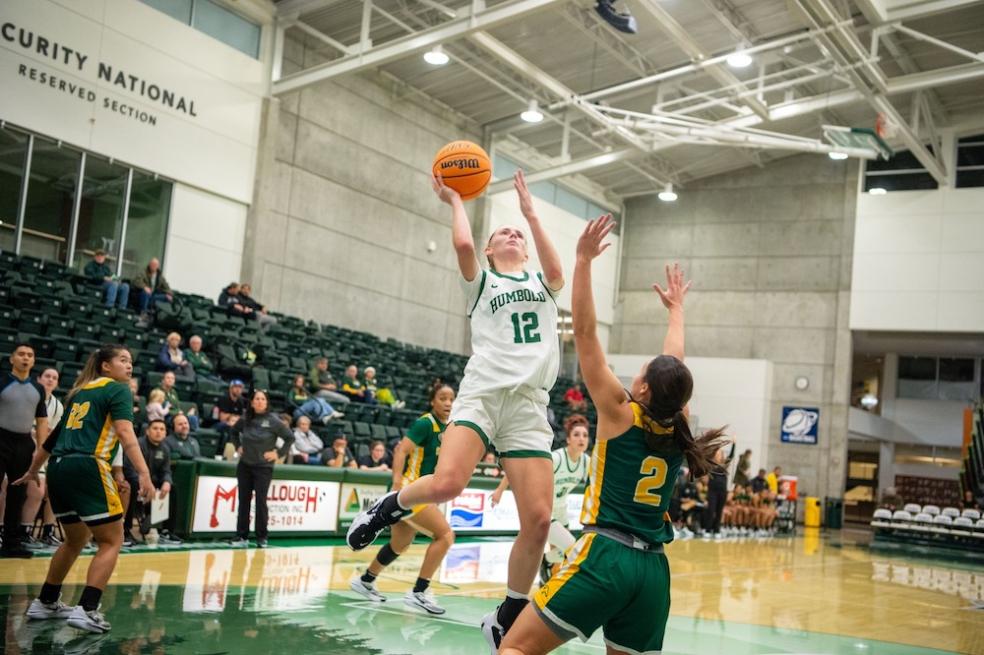 emilia long jumps above opponet with basketball in hand