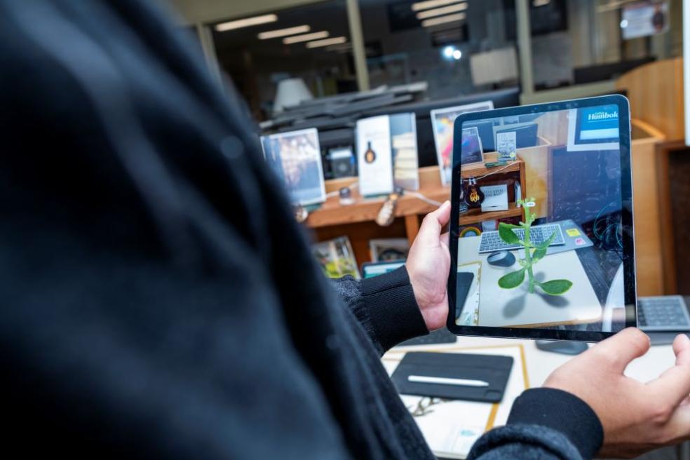 A photo a student holding an electronic tablet using the Library's 3D Digital Herbarium. 