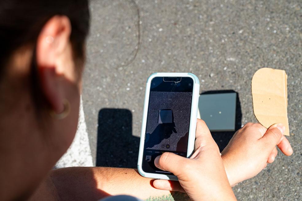 A student captures a photo of a pinhole projection.