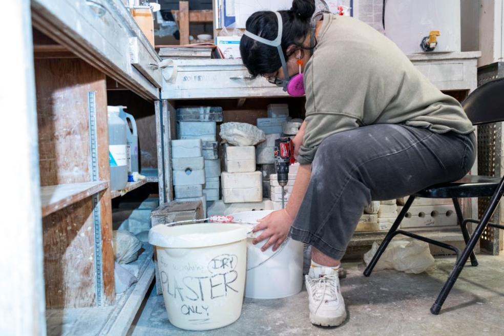a photo of a student sitting down while mixing silicone together to create a mold.