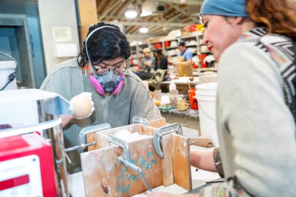 A photo of students working on creating ceramic mugs.