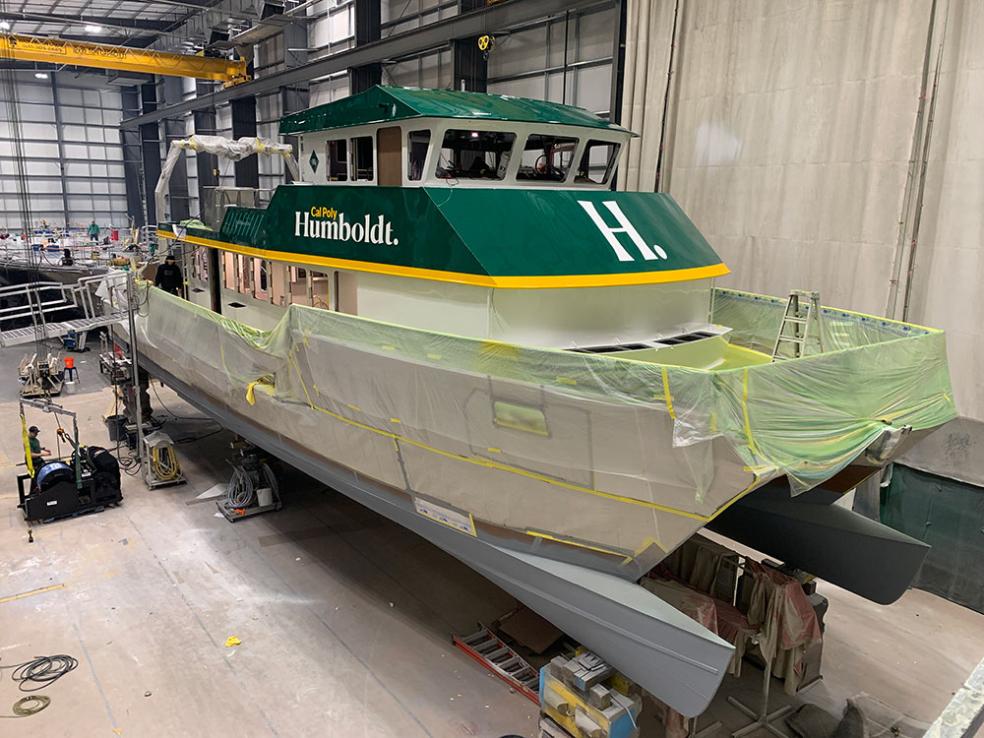 the R/V North Wind in a warehouse with plastic sheeting covering its lower half